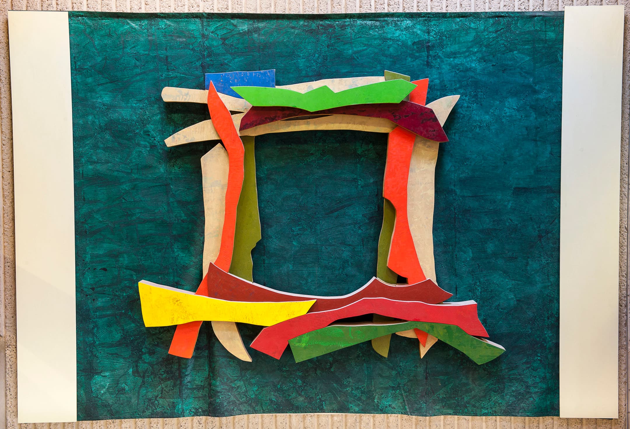 Abstract artwork featuring a variety of colorful, layered shapes arranged to form an irregular frame against a textured teal background. The shapes include shades of red, green, beige, orange, and yellow, adding depth and dimension to the piece. The composition is bordered by white sections on the left and right.
